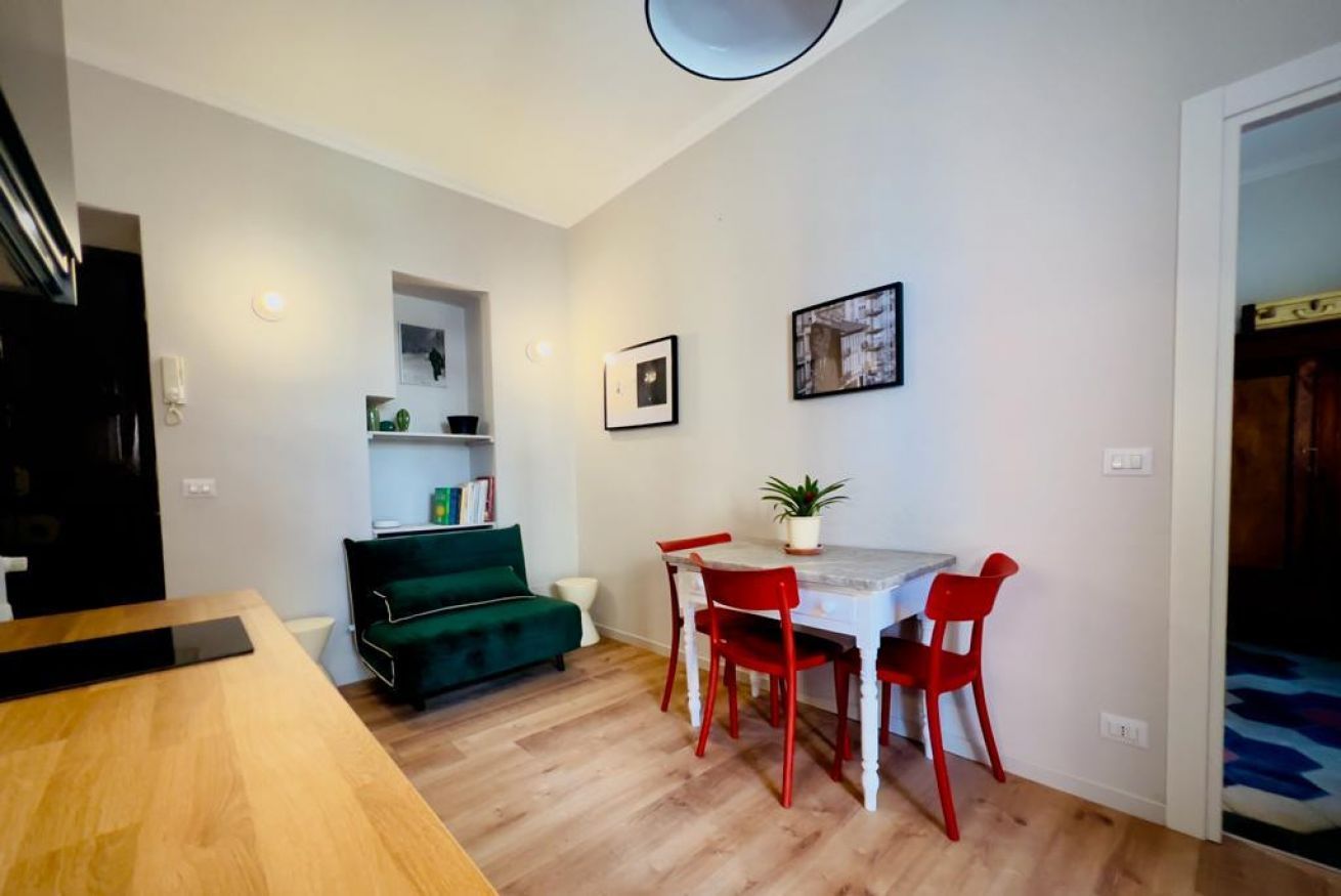 Un comedor con una mesa de madera y sillas rojas, un sofá verde y un techo blanco.