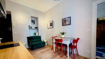 Un comedor con una mesa de madera y sillas rojas, un sofá verde y un techo blanco.