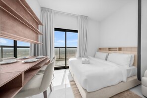 Ein Hotelzimmer mit einem Bett, einem Schreibtisch mit Stühlen und Blick auf die Landschaft.