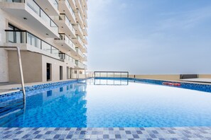 Ein Schwimmbecken mit klarem, blauem Wasser, umgeben von einem modernen Gebäude mit Balkonen.