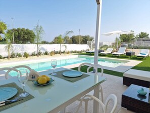 A poolside dining area with a table set for two, a glass of water, and a plate of lemons. - Villa Elisia - Villetta con Piscina Privata (Augusta)