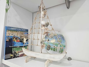 A shelf with a decorative sailboat model and a cookbook titled 'La Cucina Siciliana'. - La Vela Recanati-studio con Accesso Alla Spiaggia (Giardini Naxos)
