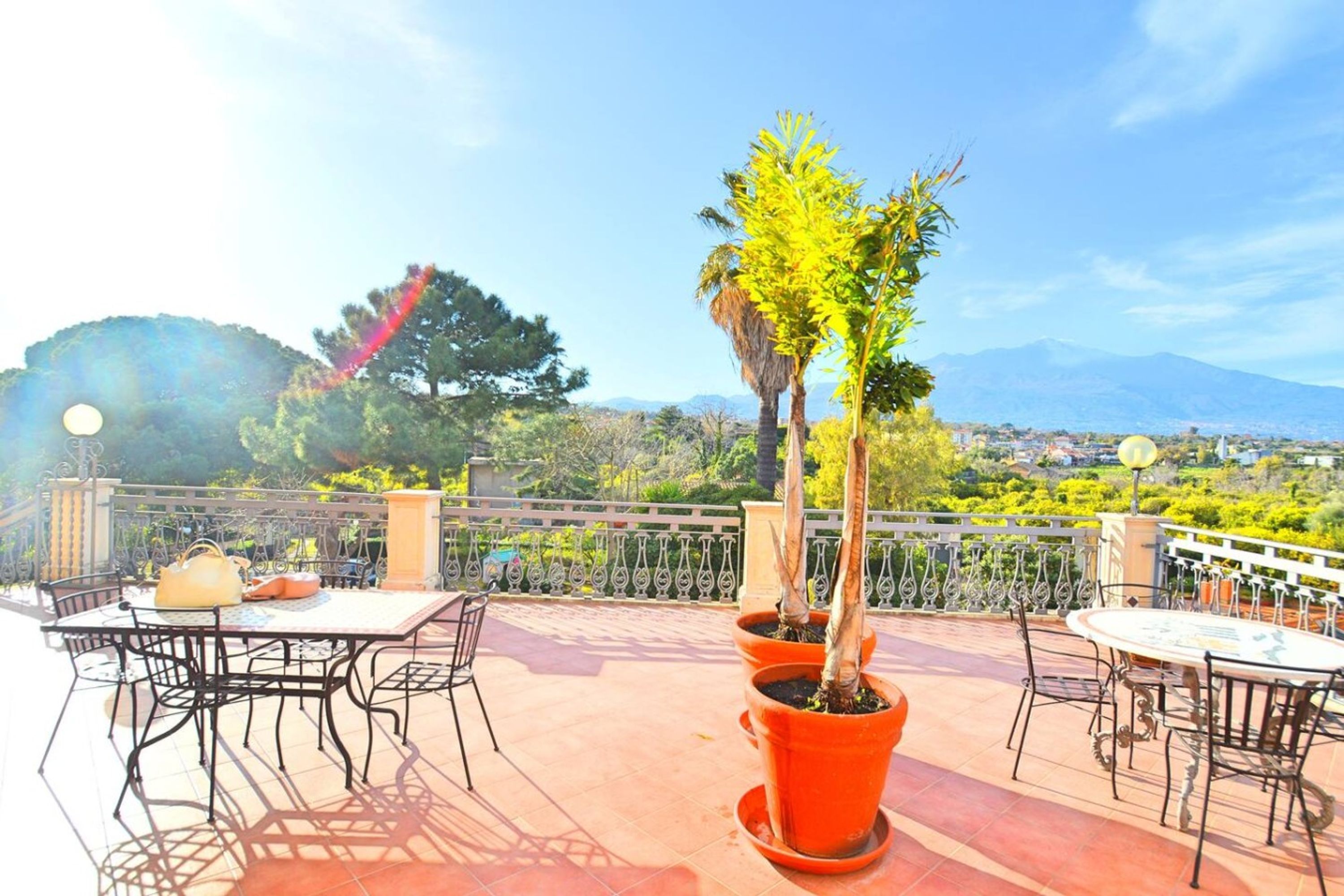 Una terrazza con posti a sedere all'aperto, piante in vaso e vista su un paesaggio montano.