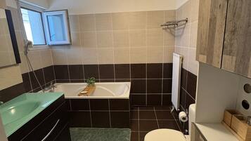 Une salle de bain avec une baignoire, des toilettes et un tapis vert.