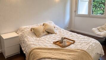 Une chambre à coucher avec un lit, des tables de chevet, une fenêtre donnant sur un beau paysage et un fauteuil.