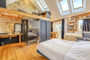 A bedroom with a loft area, a large bed, a wooden desk, and a bookshelf. - Hostcare - Maison unique dans ancien bar rénové (Nantes)