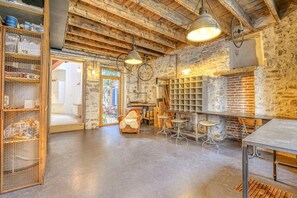 A rustic interior with exposed brick walls, a wooden ceiling, and a bar area with stools. - Hostcare - Maison unique dans ancien bar rénové (Nantes)