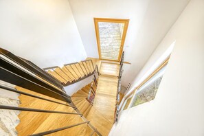 A spiral staircase with wooden steps and metal railings, leading to a small window with a view of the outside. - Hostcare - Maison unique dans ancien bar rénové (Nantes)