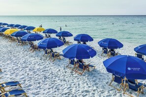 A beach with rows of blue and yellow umbrellas and beach chairs. - 🌅Walk to Beach | Gulf & Lake Views | Pelican Terrace 905🌴 (Destin)