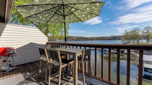 A deck with a table and chairs, a grill, and a view of a lake. - Lake Life Starts Here! Free Boat Slip & Epic Views (Osage Beach)
