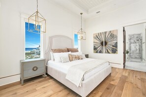 Ein Schlafzimmer mit einem großen Bett, zwei Nachttischen, einem Fenster mit Blick und zwei Pendelleuchten.