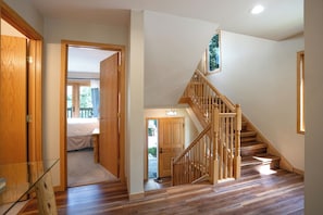 A wooden staircase leading to a second floor, a bedroom with a bed and a view of the outdoors, and a door leading to a garage. - Snowflake Lift 3-Min Walk | Main St | Private Hot Tub (Breckenridge)