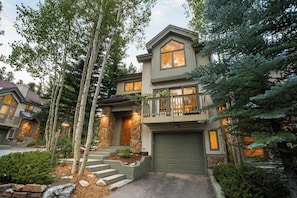 A multi-story house with a stone facade, a front porch with steps, and a garage. - Snowflake Lift 3-Min Walk | Main St | Private Hot Tub (Breckenridge)
