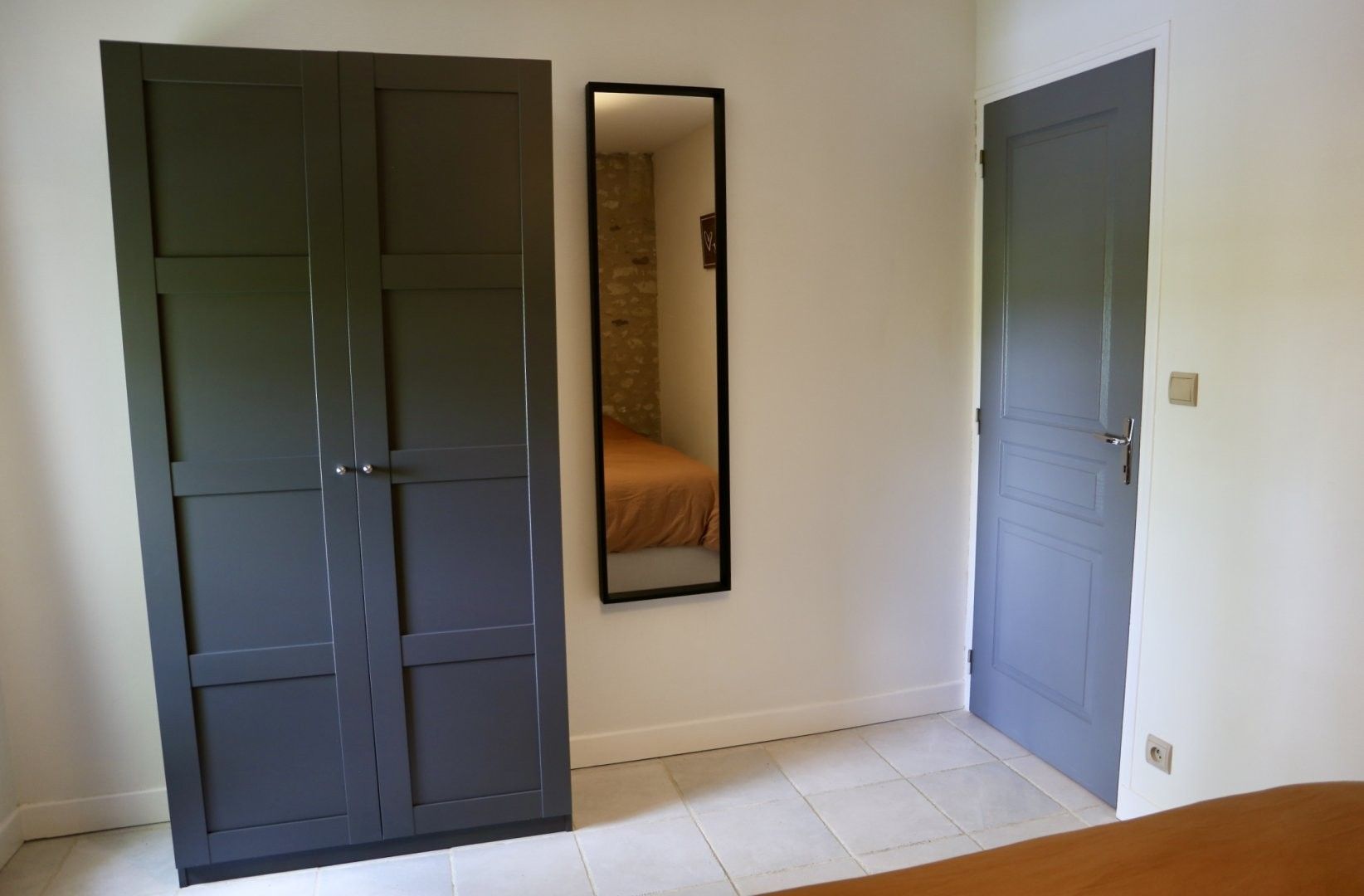 Una habitación con armario, espejo y puerta.