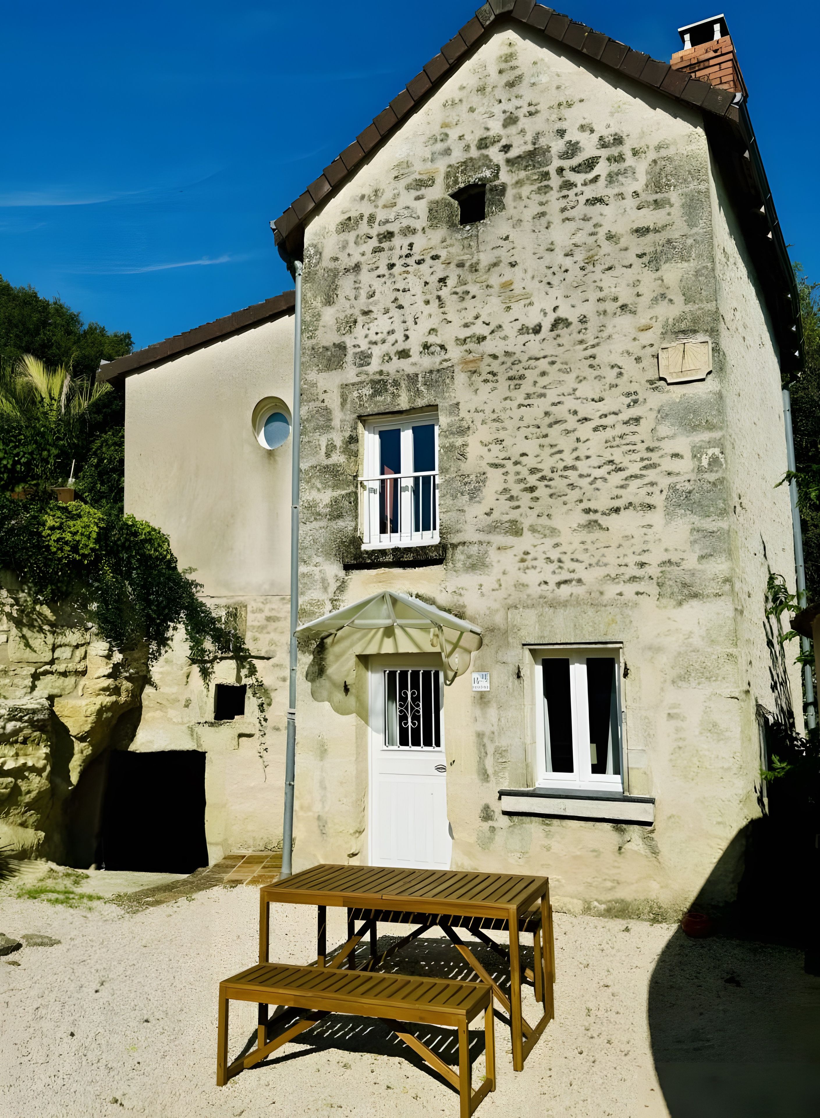 Un edificio de piedra de dos pisos con una puerta blanca, dos ventanas y un balcón pequeño.