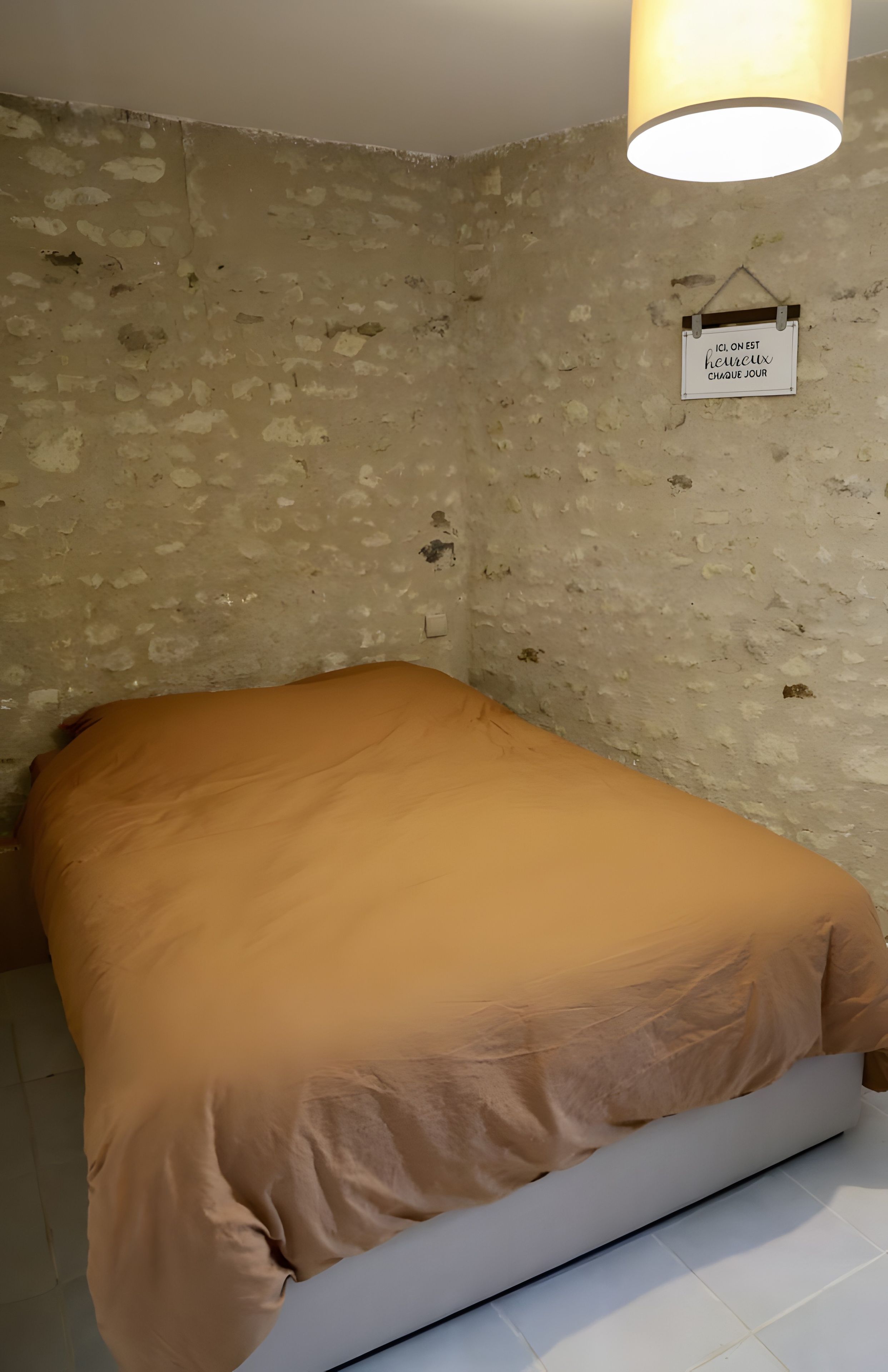 A room with a bed, a wall-mounted light fixture, and a sign with text.