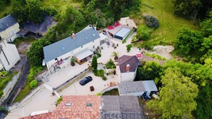 An aerial view of a property with a large open patio area, a swimming pool, and a small building with a sloped roof.