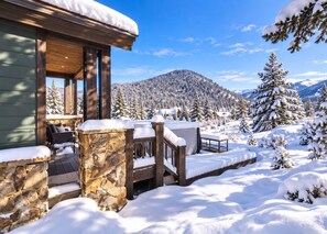 A wooden cabin with stone walls, a porch, and a view of snow-covered mountains. - Serene home on 2 Acres, Minutes to Slopes, Private Hot Tub (Breckenridge)