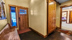 A hallway with a wooden bench, a door with glass panels, and a wooden door leading to another room. - Serene home on 2 Acres, Minutes to Slopes, Private Hot Tub (Breckenridge)