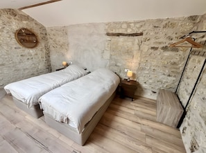 Un dormitorio con dos camas, paredes de piedra y suelo de madera.
