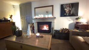 Una sala de estar acogedora con chimenea, un pequeño árbol de Navidad y un cuadro en la pared.