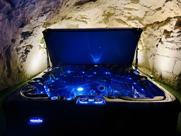 A hot tub with a control panel and a 'VENDOM' label, set against a cave-like background.