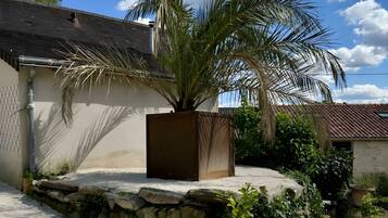 Un edificio con un muro de piedra, una palmera y plantas en macetas.
