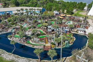 An aerial view of a resort with a water body, wooden walkways, and palm trees. - 🌊 Gulf Views! Beachside Pool☀️Private Beach Access - Emerald Isle 612 (Fort Walton Beach)