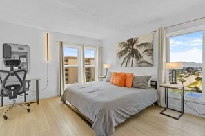 Ein Hotelzimmer mit Bett, Schreibtisch mit Stuhl, großem Fenster mit Aussicht und einem Gemälde an der Wand.