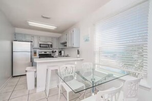 A modern kitchen with white cabinetry, a glass dining table, and a built-in oven. - ⭐Gulf Views-Hot Tub-Private Balcony-1BR+Bunk Summerspell 301⭐ (Miramar Beach)