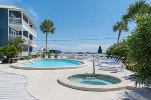 A pool area with two pools, lounge chairs, and a building with balconies. - ☀️Summer Breeze 302 | Gulf Views~Pool+Hot Tub~Balcony~Walk to Beach⛱️ (Miramar Beach)