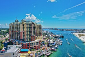 A multi-story hotel with a central courtyard, located near a marina with boats and a beach. - 🌊 2 Balconies | Gulf & Crab Island Views | 3BR Emerald Grande W1129 ☀️ (Destin)