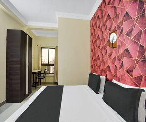 A hotel room with a bed, a desk, and a chair. - Deluxe Hotel Radhika Inn (Danapur)