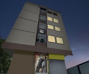 A multi-story building with a modern architectural design, featuring a prominent entrance with a glass facade and a sign indicating 'Collection & Company Services.' - Deluxe Hotel Radhika Inn (Danapur)