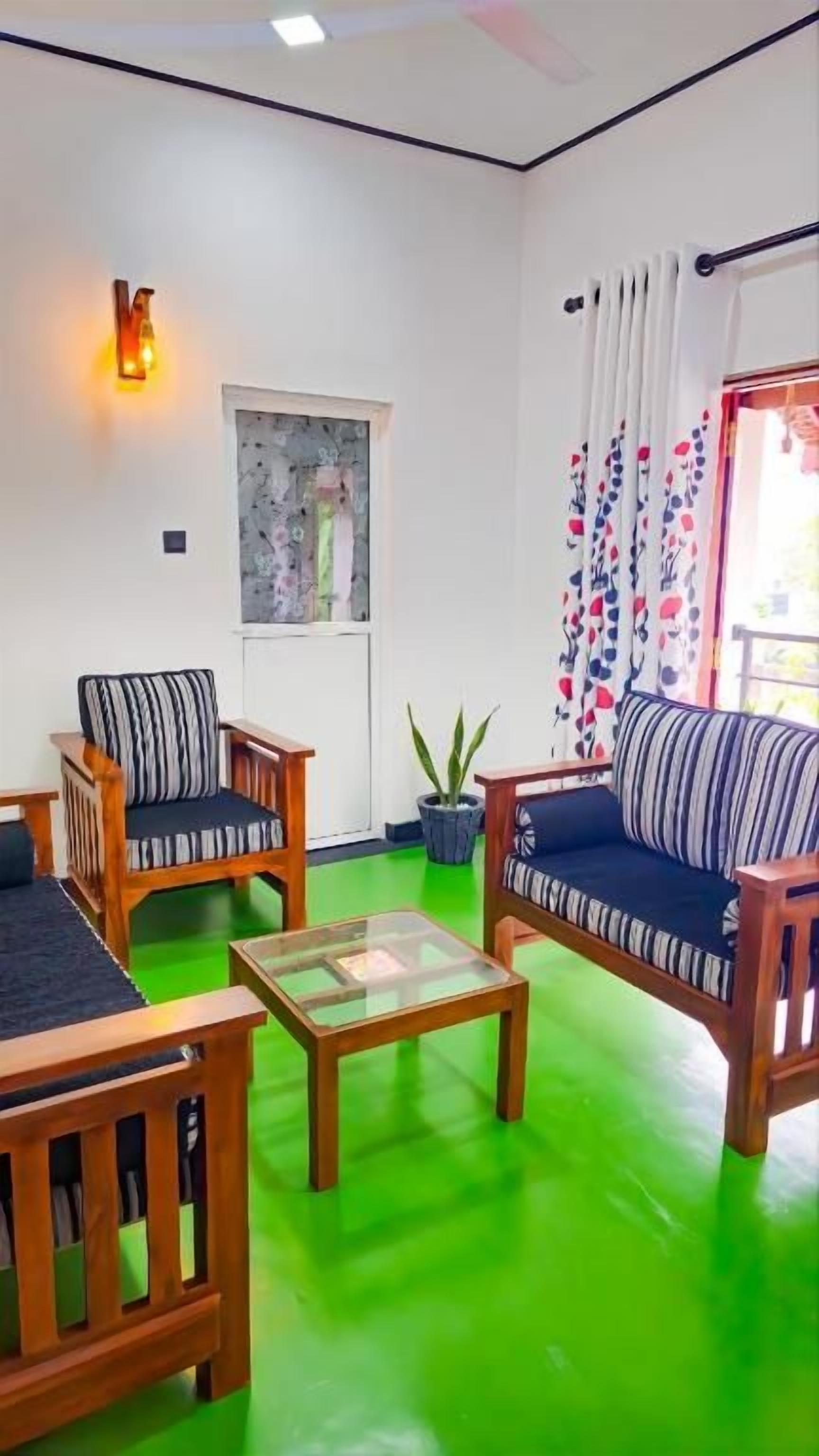 Une pièce avec un sol vert, deux canapés dotés de coussins à rayures, une table basse en bois et une plante en pot.