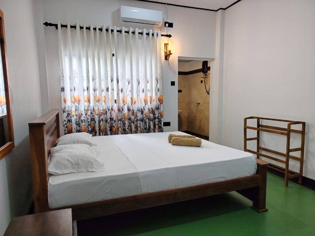 A single bed with a wooden frame, white bedding, and a green floor.