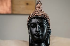 Eine Statue mit strukturierter Oberseite und glatter Oberfläche vor neutralem Hintergrund.