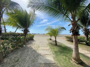 A pathway leading to a beach with palm trees and a clear sky. - Comfortable Apartment Near the sea in Cartagena (Cartagena)