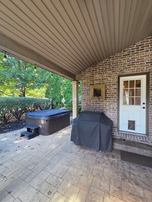 Eine Außenpatio mit Ziegelwand, Grillhaus und Whirlpool.