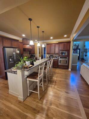 A kitchen with a central island, wooden cabinets, a refrigerator, and a microwave. - 10 Minute drive from Keeneland - Spacious 5-bedroom house in Nicholasville (Nicholasville)