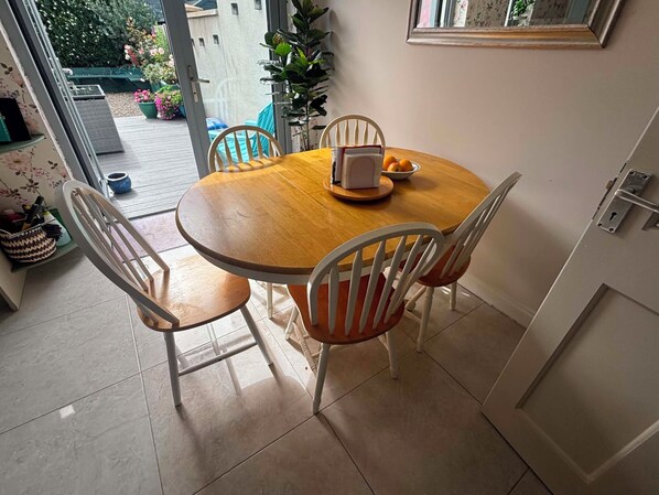 A dining area with a round wooden table, four white chairs, and a laptop on the table.