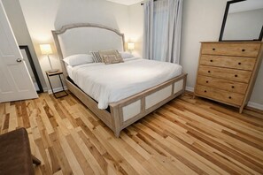 A bedroom with a wooden bed, a dresser, and a nightstand with a lamp. - Park Place, Carriage B - Ground‑Floor Courtyard Retreat Near Forsyth Park (Savannah)