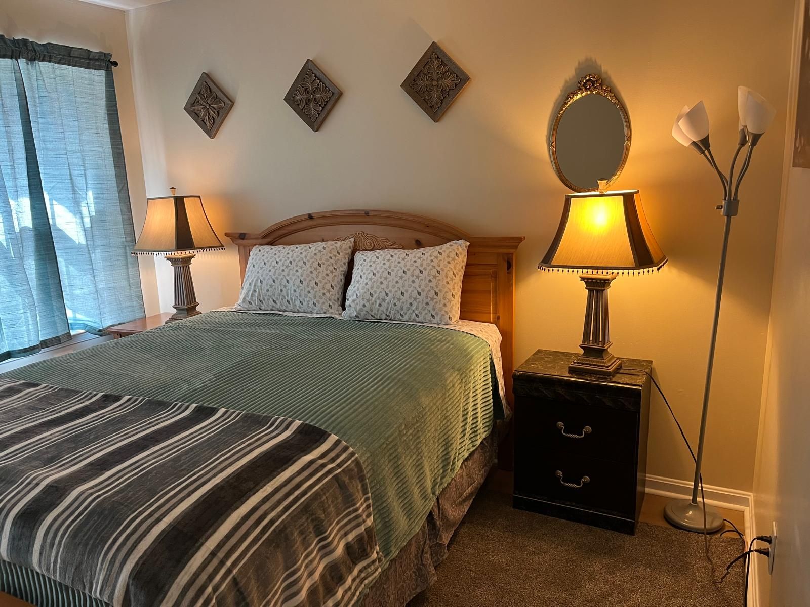 Un dormitorio con cama, lámparas de noche, mesitas de noche y detalles decorativos en la pared.