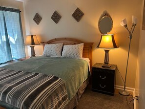 Un dormitorio con cama, lámparas de noche, mesitas de noche y detalles decorativos en la pared.