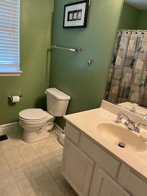 Un baño con inodoro, lavamanos y cortina de ducha.