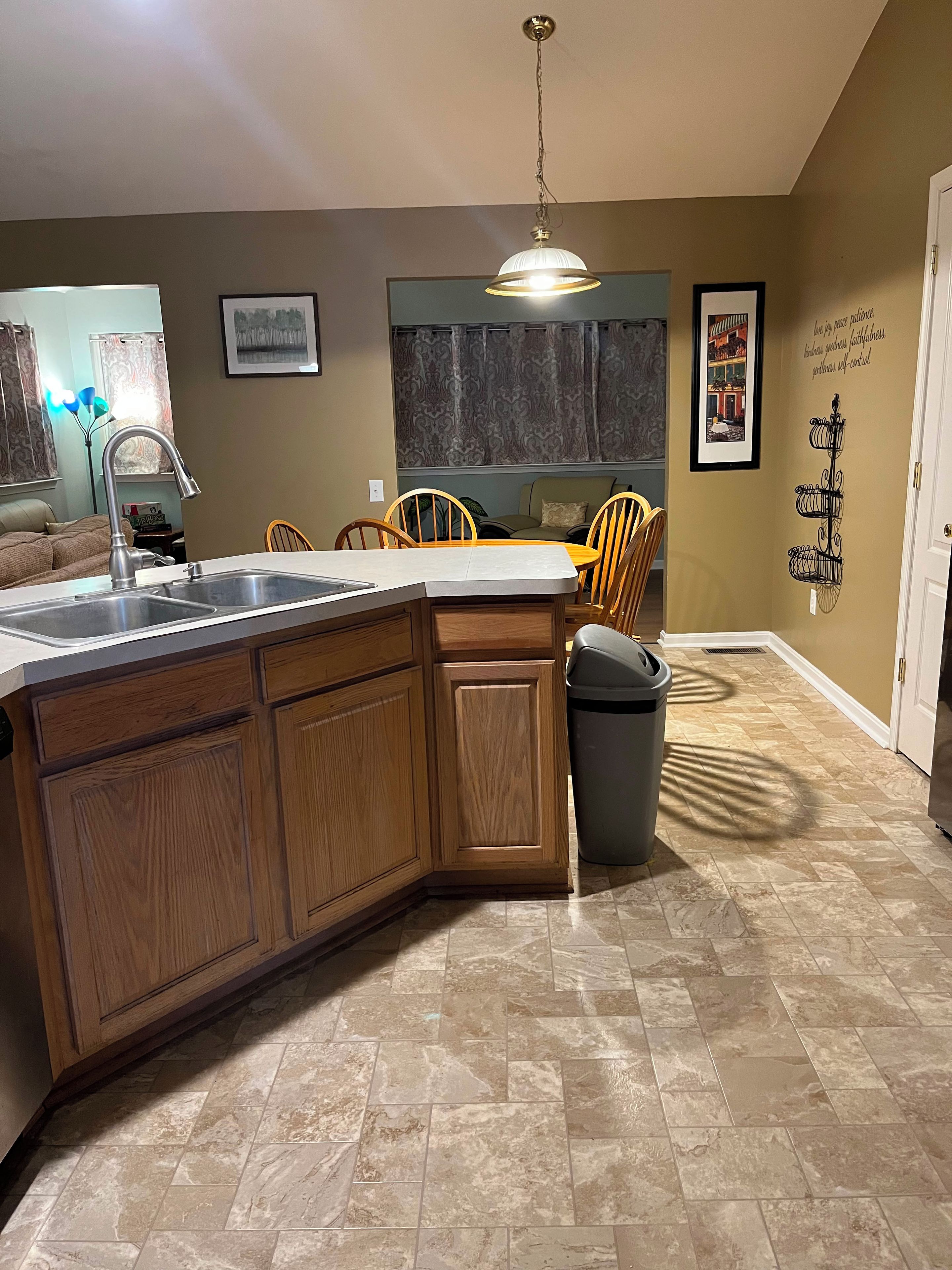 Una cocina con armarios de madera, un lavamanos y una zona de comedor con sillas.