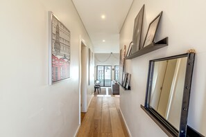 Ein Flur mit Holzboden, ein Essbereich mit Tisch und Stühlen sowie ein großer Spiegel an der Wand.
