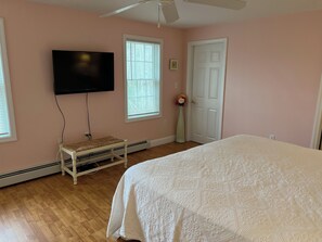 Een slaapkamer met een bed, een televisie, een verwarming en een deur.