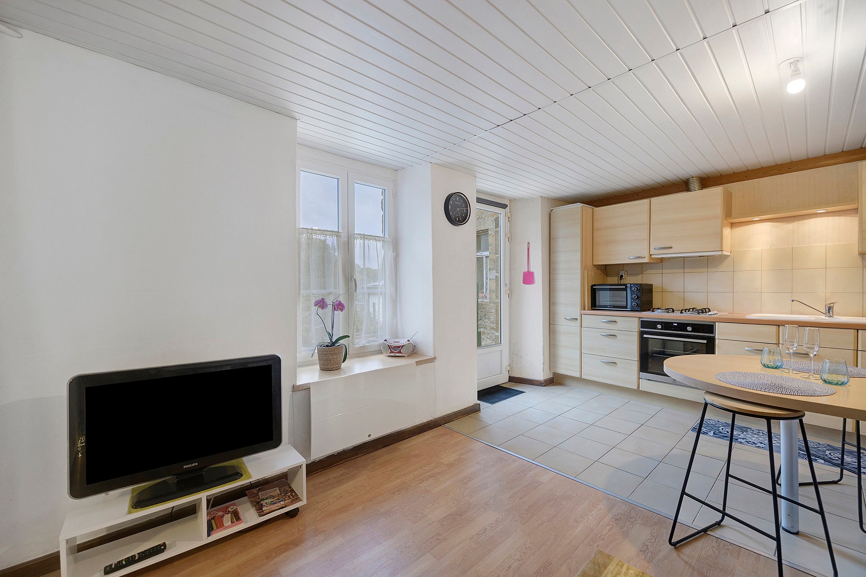 Une cuisine moderne avec des meubles en bois, un four à micro-ondes encastré et un coin repas comprenant une table et des chaises.