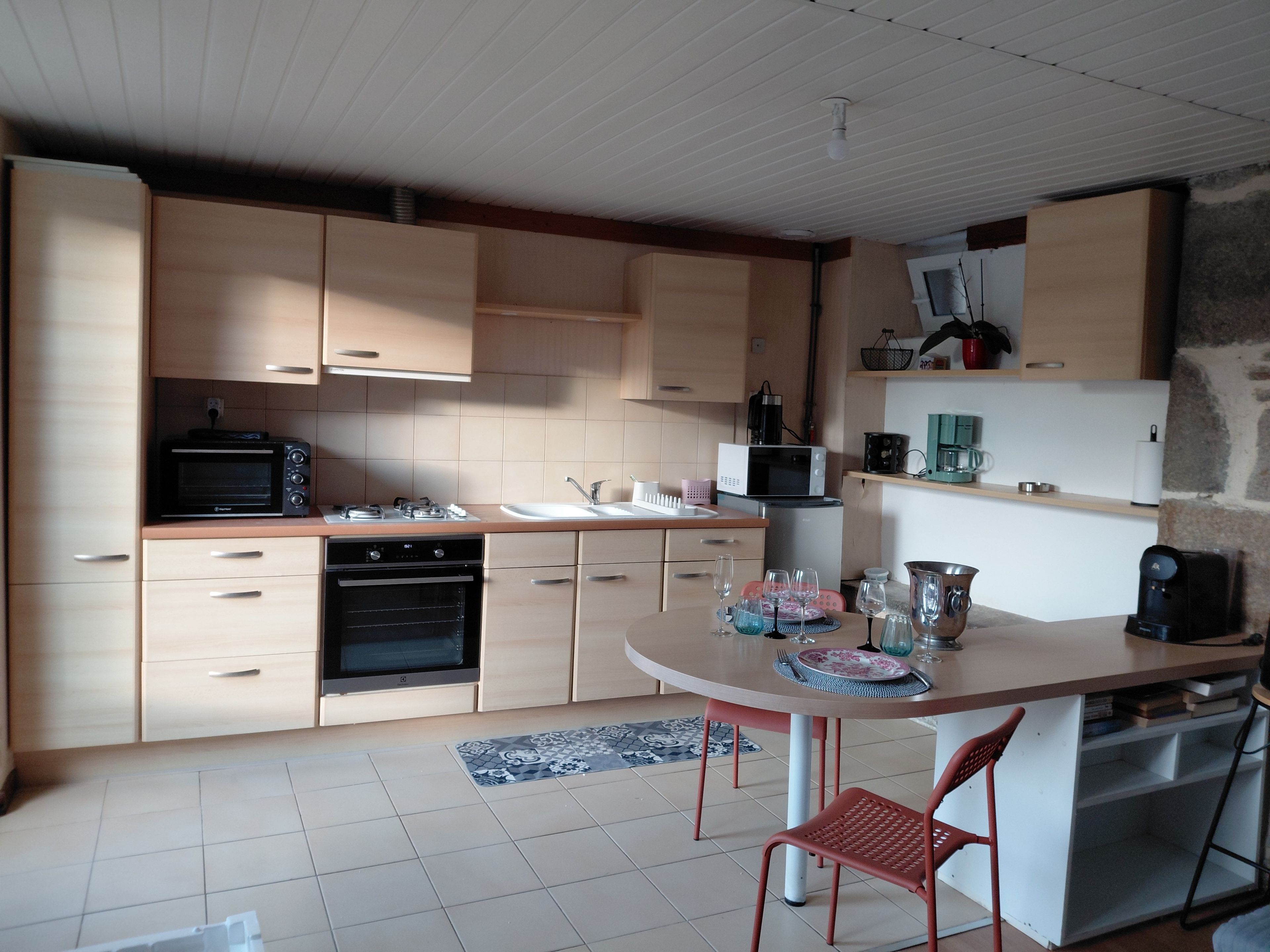 Une cuisine moderne dotée d’appareils électroménagers intégrés, un coin repas avec une table et des chaises, et un mur d’accent en pierre.